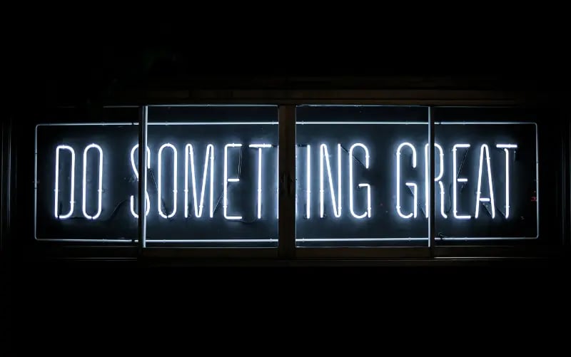 "Do Something Great" in weißen Neonlichtern auf schwarzem Hintergrund.