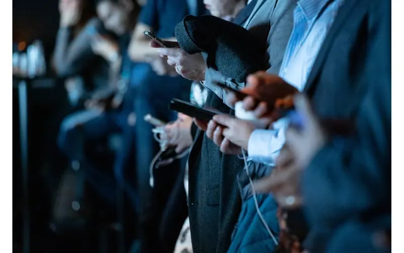 Männer in Anzügen halten ihre Smartphones in der Hand und verfolgen einen Kommunen Live Blog von Tickaroo, um über die wichtigsten kommunalen Informationen zu verfolgen.