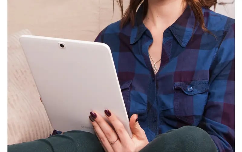 Woman reading a liveblog on a tablet on her couch.