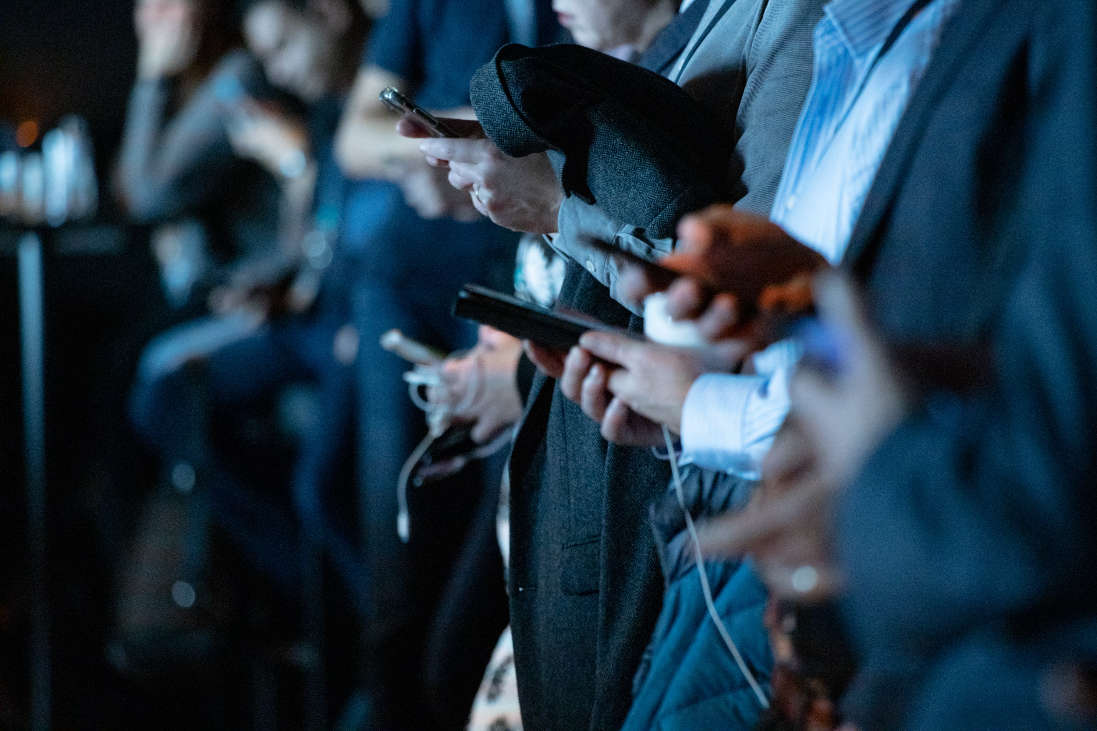 Männer in Anzügen halten ihre Smartphones in der Hand und verfolgen einen Kommunen Live Blog von Tickaroo, um über die wichtigsten kommunalen Informationen zu verfolgen.