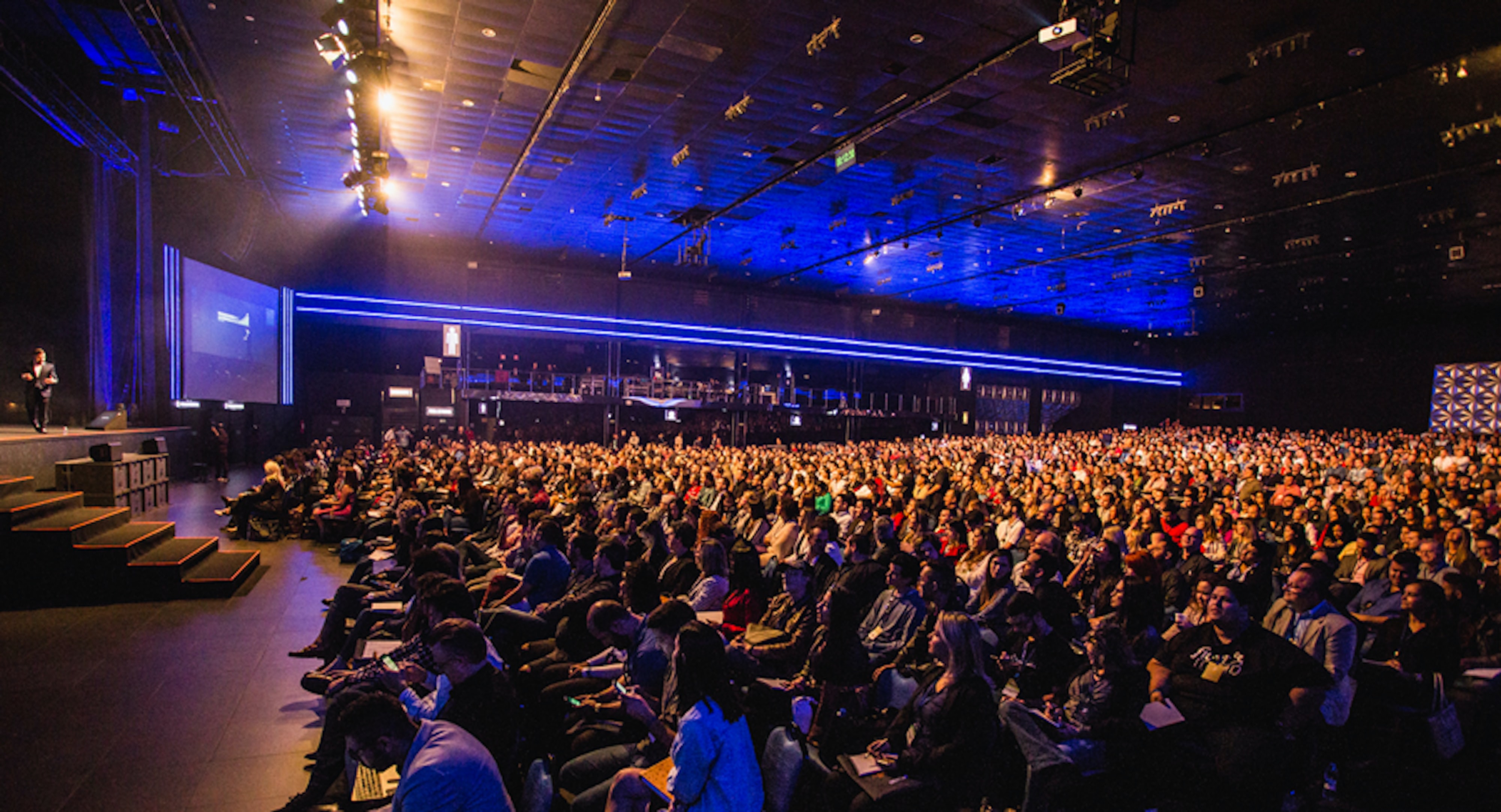Eine große Halle mit vielen sitzenden Menschen. Vorne auf der Bühne steht ein Speaker, der über die neuesten technologischen Entwicklungen spricht. Die Convention wird mit einem Liveblog verfolgt und ermöglicht dadurch auch Menschen, die nicht live vor Ort dabei sein können, eine seriöse Berichterstattung des Events in Echtzeit.