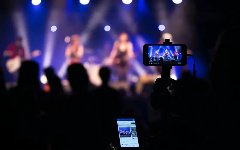 Fans in a crowd filming a concert with their mobile devices