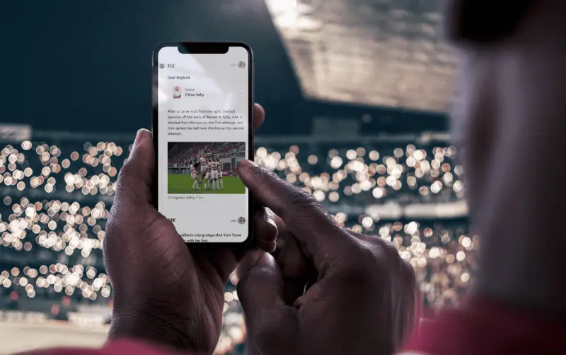 Ein Fan bei einem Fußballspiel erhält zusätzliche Informationen aus einem Liveblog des Spiels.