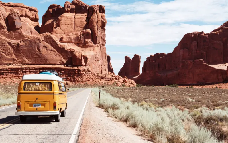 A yellow VW bus drives in the desert. Roadtrips are great opportunities for creating travel liveblogs. 