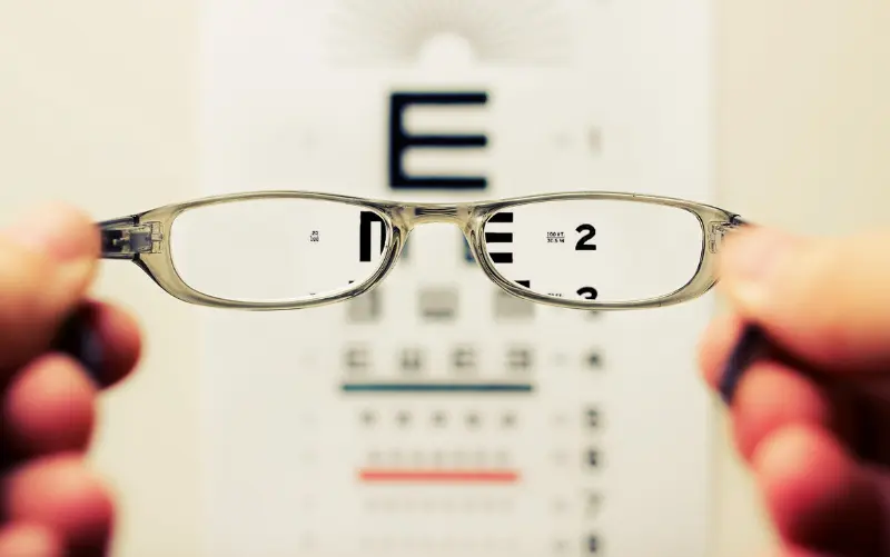A person wearing glasses to improve vision and see small letters