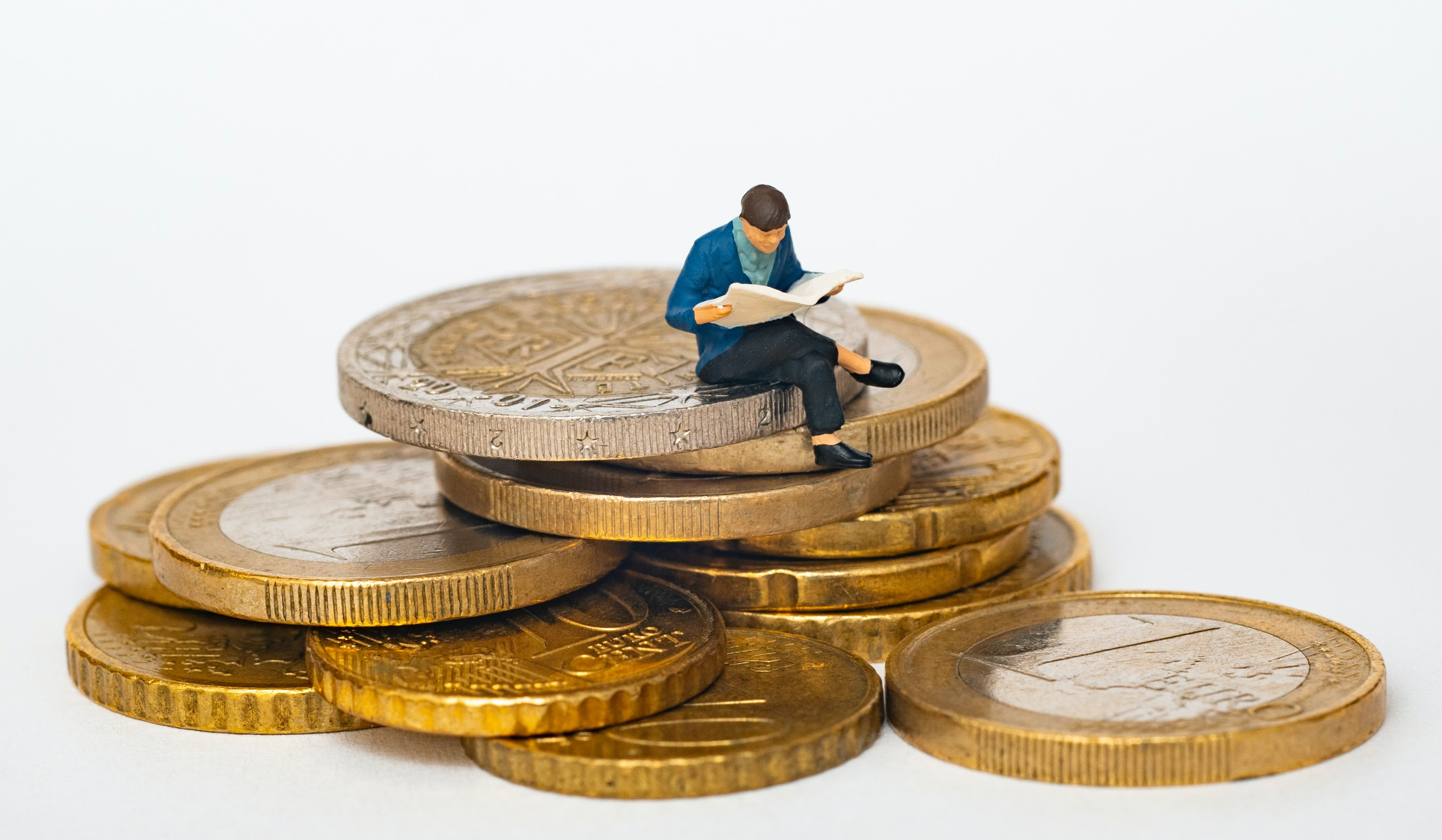 A little man sits on a pile of Euros reading. He is researching how he can best monetize his Tickaroo Live Blogs. 