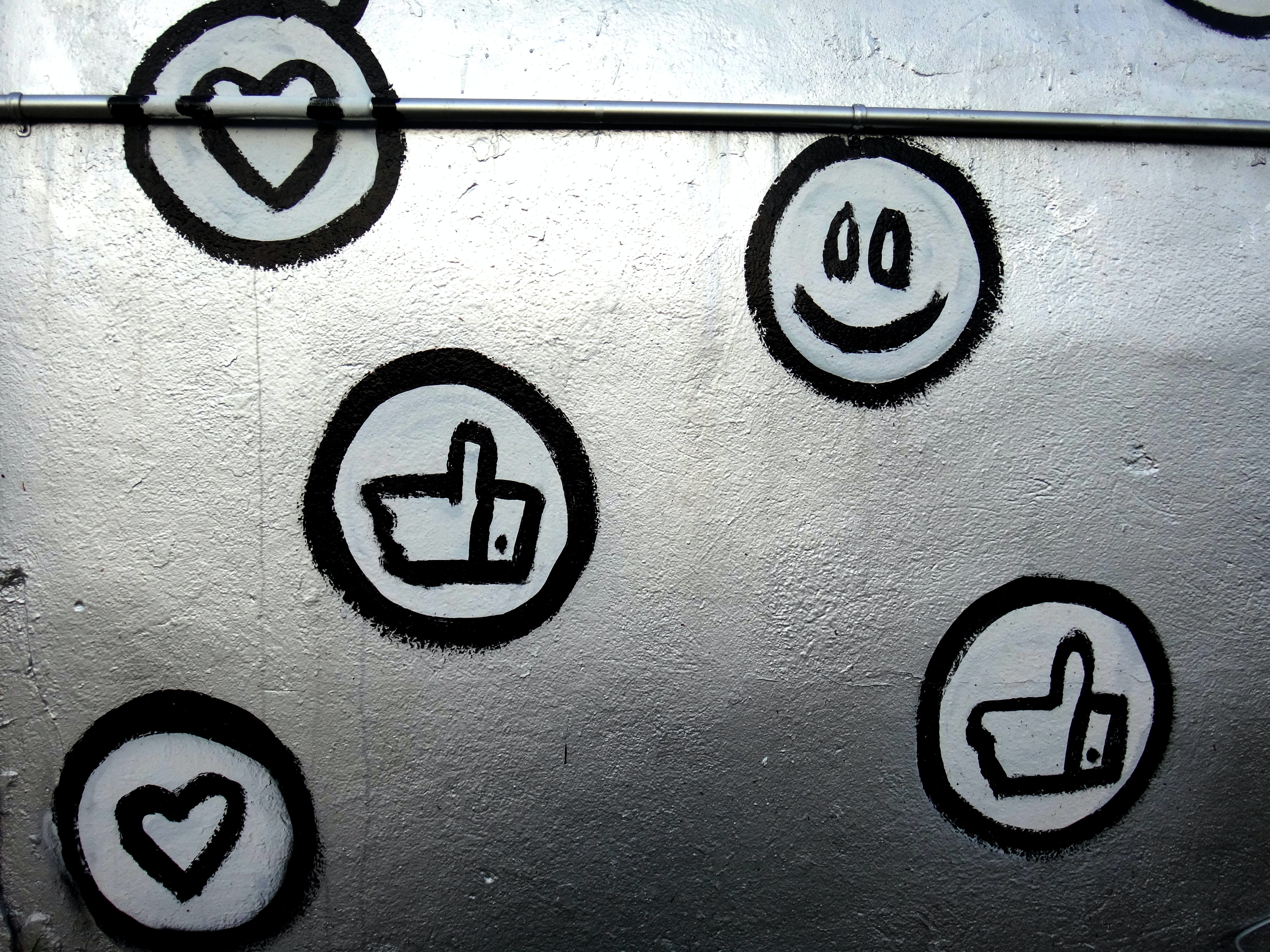 Eine Wand mit selbstgezeichneten Emojis. Man sieht ein grinsendes Emoji, ein Herz und einen Daumen nach oben. So reagieren auch eure Bürger, wenn ihr eure Kommunalprojekte im Kommunen Live Blog dokumentiert und auf Social Media teilt. 