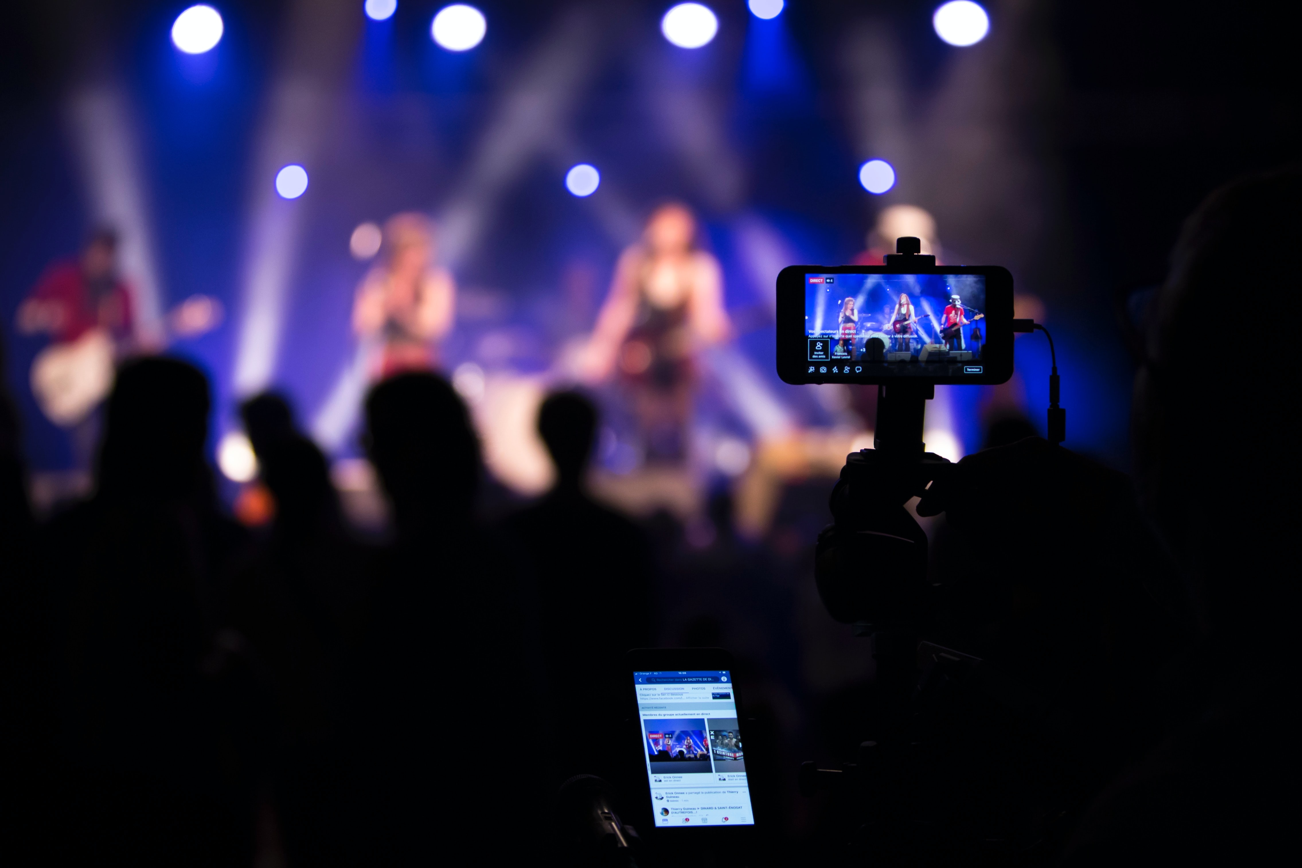 Fans in a crowd filming a concert with their mobile devices
