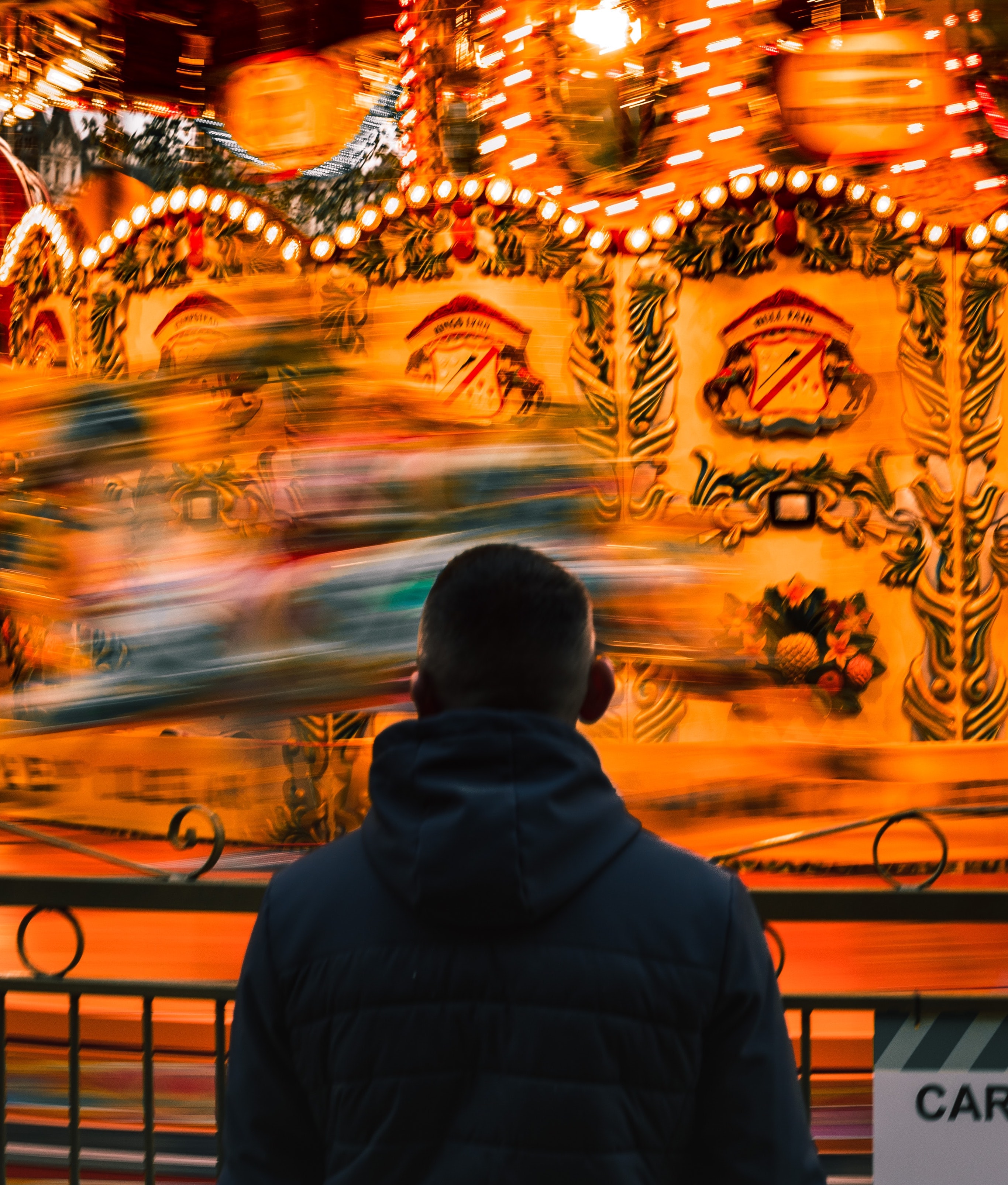 A person stands in front of a quickly-moving carousel in London.